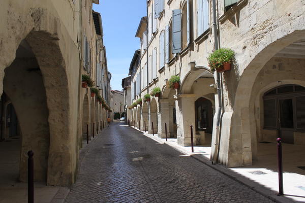 In dieser langen, schmalen Straße stehen dicht an dicht alte französische Häuser mit Torbögen.