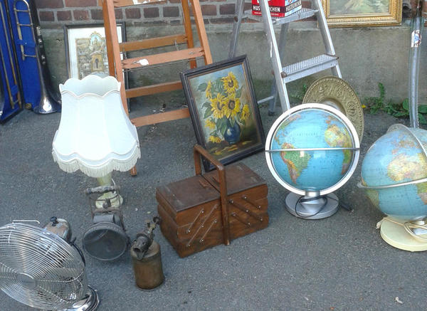 Verschiedene Flohmarktartikel werden zum Kauf angeboten. Eine Lampe, ein Globus, eine Bild und ein Nähkästchen.