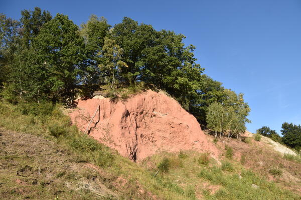 An den rötlichen Gesteinsformationen in der Schlucht  sind verschiedene geologische Gesteinsschichten sichtbar.
