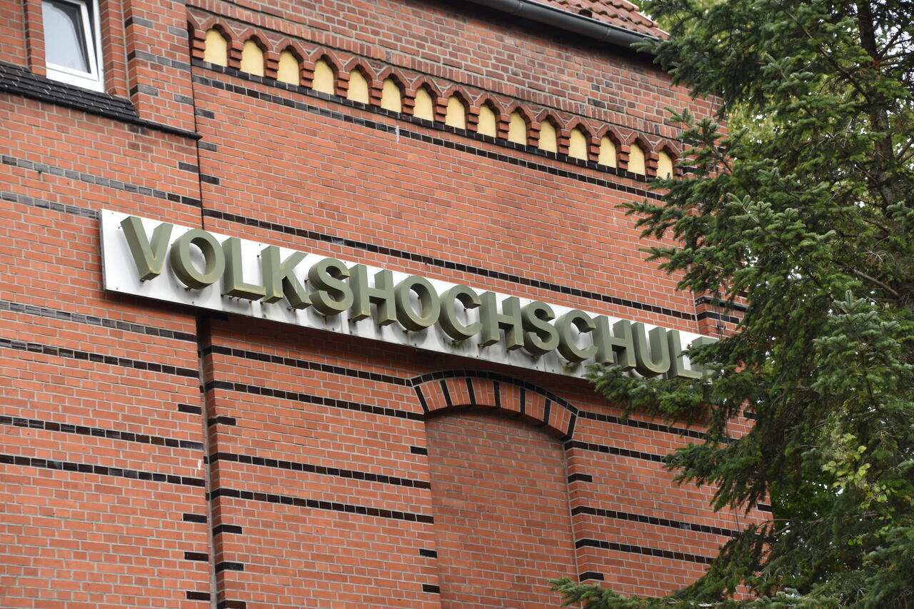 Volkshochschule steht in großenen einzelnen dreidimensionalen Buchstaben oben an dem Ziegelgebäude in der Bismarckstraße 13.