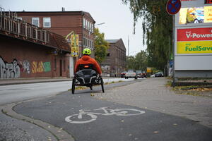 Ein Mann befährt mit einem Liegefahrrad mit drei Rädern den Radweg in der Berliner Straße.