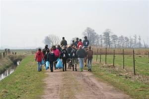 Ein Gruppe Jugendlicher, zum Teil zu Pferd, mit gefüllten Müllsäcken.