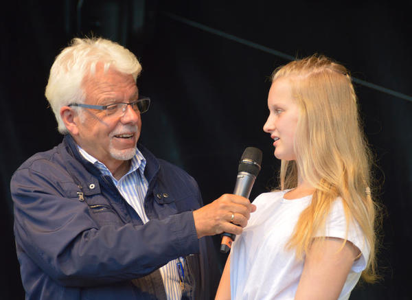 Bild vergr&ouml;&szlig;ern: Der Rundfunk Moderator befragt die Jugendliche auf der B&uuml;hne des plattdeutschen Festivals.