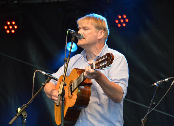 Auf der Konzertbühne des plattdeutschen Festivals spielt ein Mann Gitarre und singt in ein Mikrofon.