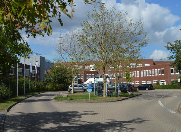 Bild vergr&ouml;&szlig;ern: Vor dem roten Geb&auml;ude parken einige Autos im Wendekreis.