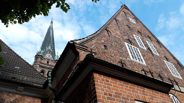 Der Kirchturm ragt in den blauen Himmel. Der Giebel der Kirche ist aus rotem Backsteinen gemauert.