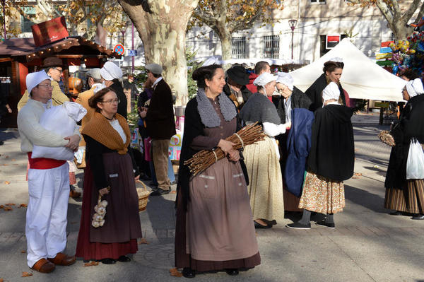 Auf dem Weihnachtsmarkt der Partnerstadt in Frankreich trägt eine Gruppe von Frauen traditionelle Trachten.