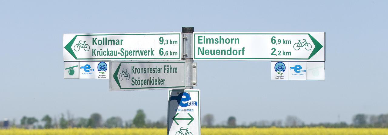 Radwegweiser vor blauem Himmel. Nach Elmshorn sind es 6,9 km.