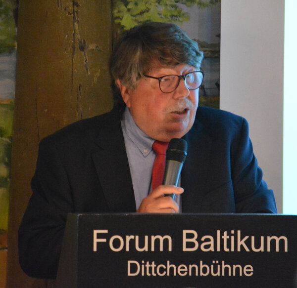 Raimar Neufeldt steht im Anzug an einem Pult des Forums Baltikum und redet in ein Mikro.