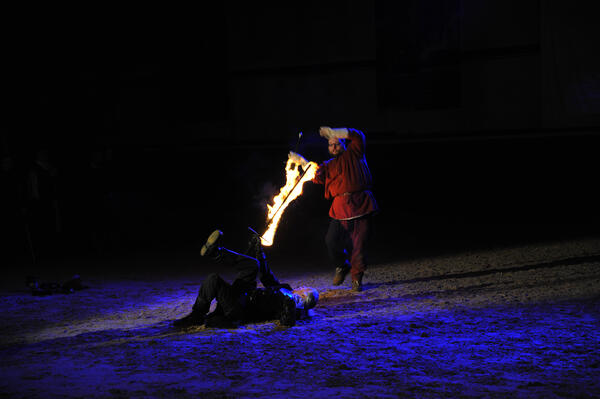 Zwei kostümierte Schwertkämpfer liefern sich ein Duell mit brennenden Schwertern.