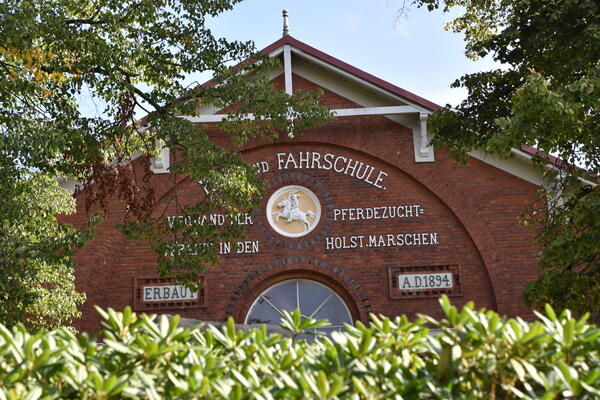 Der Giebel des historischen Gebäudes der Reit- und Fahrschule zeigt den Namen,  einen Reiter und das Erbauungsjahr 1894.