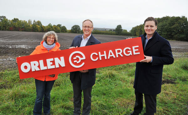 Bild vergr&ouml;&szlig;ern: Symboischer Spatenstich f&uuml;r ORLENS E-Ladepark in Elmshorn: Auf der gr&uuml;nen Wiese stehen Elmshorns Wirtschaftsf&ouml;rderin Angelika von Bargen, Elmshorns Oberb&uuml;rgermeister Volker Hatje und ORLENS Director E-Mobility&Business Development Benedikt Brandi.