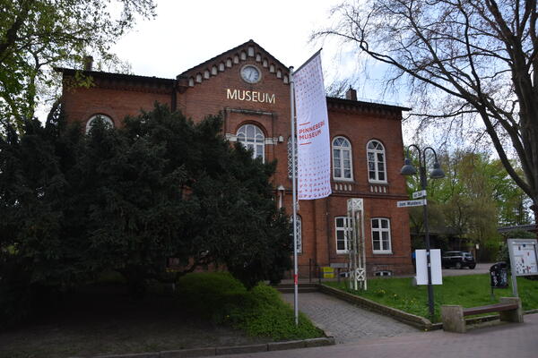 Bild vergr&ouml;&szlig;ern: Zweist&ouml;ckiges rotes Backsteingeb&auml;ude mit goldenem Schriftzug "Museum"