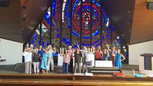 Bild vergr&ouml;&szlig;ern: Gruppenbild von Personen in bunter Kleidung vor einem Kirchenaltar.