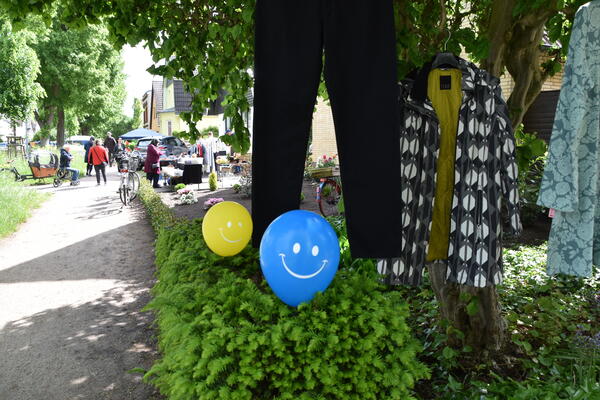 Idyllischer Gehweg mit vielen B&auml;umen entlang der Wrangelpromenaden, wo bunte Luftballons auf die Verkaufsst&auml;nde hinweisen. 