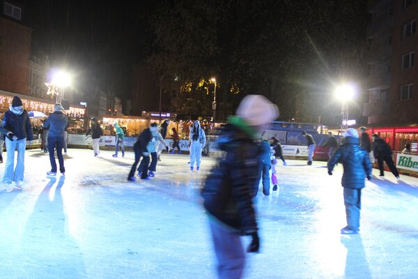Viele Menschen laufen Schlittschuh auf der Eisbahn.