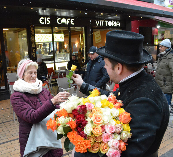 Ein Schornsteiger als Gl&uuml;cksbote verteilt Rosen an die Menschen in der K&ouml;nigstra&szlig;e.
