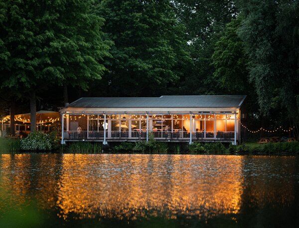 Bild vergr&ouml;&szlig;ern: Blick auf die abendlich beleuchtete Gastst&auml;tte am See.