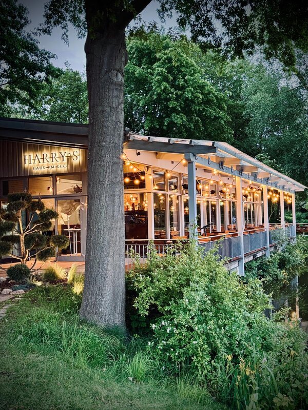 Bild vergr&ouml;&szlig;ern: Blick auf die abendlich beleuchtete Gastst&auml;tte Harry's Haus am See.