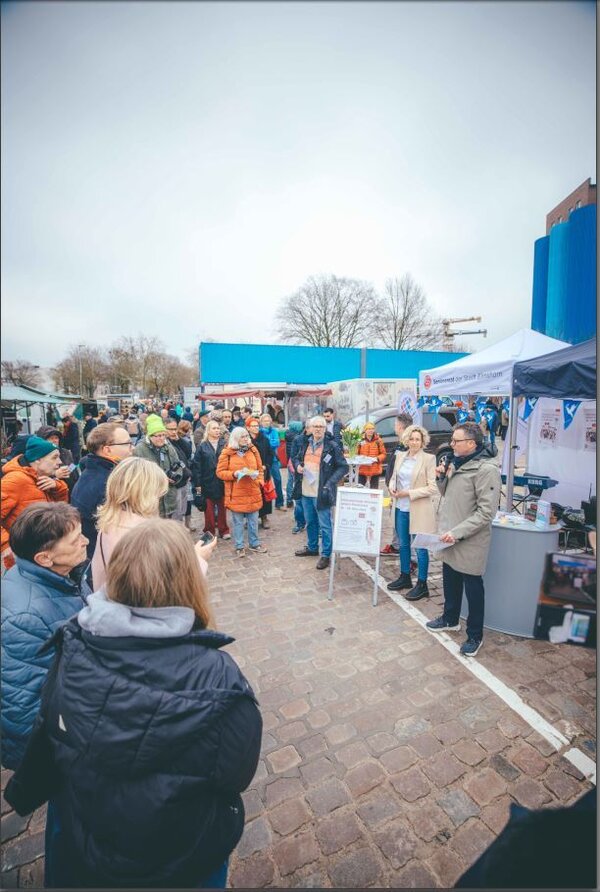 Bild vergr&ouml;&szlig;ern: Oberb&uuml;rgermeister Erik Sachse begr&uuml;&szlig;t umstehende Menschen an einem Stand auf dem Wochenmarkt.