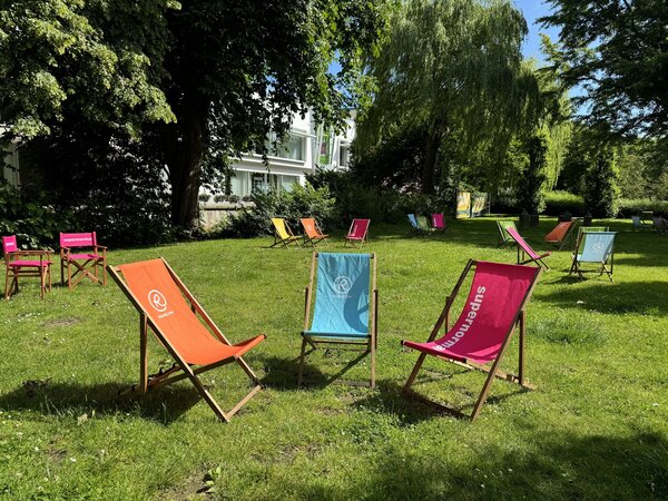 Mehrere bunte Liegest&uuml;hle auf einer Wiese im Gr&uuml;nen.