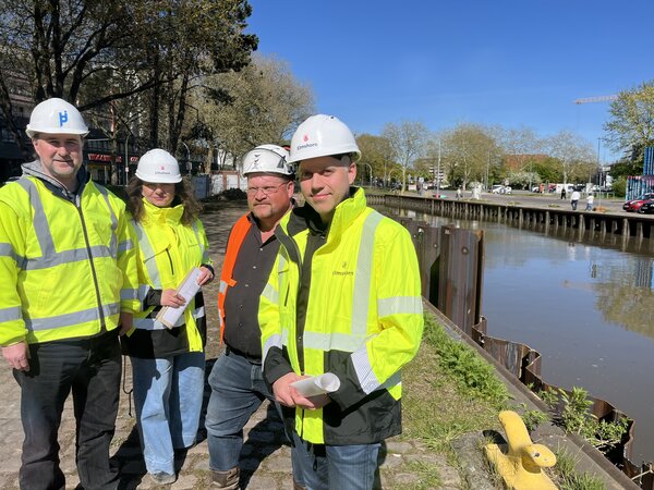 Bild vergr&ouml;&szlig;ern: Elmshorns Baustadtrat Marius Munk mit Amtsleiterin Sybille Weinmann-Klinkow und den Unternehmensvertreter Steffen Haack sowie Marcus Behrens vom Ingenieurb&uuml;ro B&ouml;ger und J&auml;ckle an der neuen Spundwand am Hafen-Nordufer.