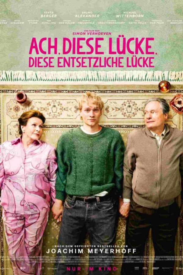 Plakat mit Angaben zum Kinofilm. Eine &auml;ltere Frau, ein junger Mann und ein &auml;lterer Mann liegen auf dem R&uuml;cken auf einem Teppich mit Fransen. 