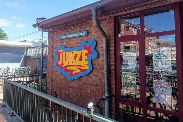 Au&szlig;enansicht der Fassade und Fensterfront des Jugendkulturzentrums Elmshorn. An der Fassade befindet sich das angebrachte JUKZE-Logo.