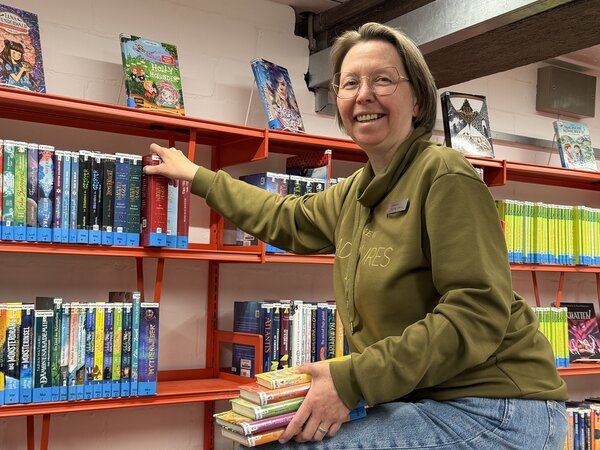 B&uuml;chereimitarbeiterin Dagmar Siering in den R&auml;umen der Stadtb&uuml;cherei Elmshorn vor einem B&uuml;cherregal.