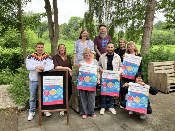 Frauen und M&auml;nner werben f&uuml;r das Somemrferienprogramm 2026 mit Plakaten.