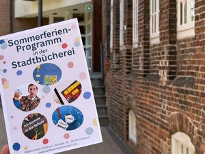 Bild vergr&ouml;&szlig;ern: Plakat zum Sommerferienprogramm der Stadtb&uuml;cherei vor dem Geb&auml;ude der Stadtb&uuml;cherei
