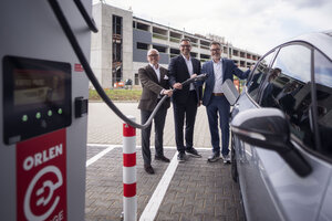 Bild vergr&ouml;&szlig;ern: Der neue ORLEN Charge E-Ladehub in Elmshorn nahe der A23 in der Werner-von-Siemens-Stra&szlig;e mit drei M&auml;nnern an der Zapfs&auml;ule.