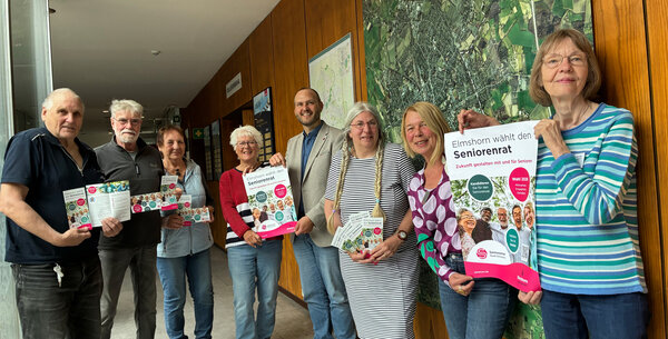 Bild vergr&ouml;&szlig;ern: Mitglieder des Seniorenrats werben f&uuml;r die Wahl 2026. Gemeinsam mit dem Ersten Stadtrat Michael Leeske und Nicola Schulz-B&ouml;deker von der Stadt Elmshorn pr&auml;sentieren sie Flyer und Plakate im Atrium des Rathauses.