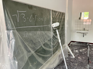 Bild vergr&ouml;&szlig;ern: Eine Malerrolle steht an eine beschriebene Tafel gelehnt im Klassenraum.