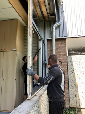 Bild vergr&ouml;&szlig;ern: Drei M&auml;nner hebeln ein gro&szlig;es Fenster aus dem Rahmen.