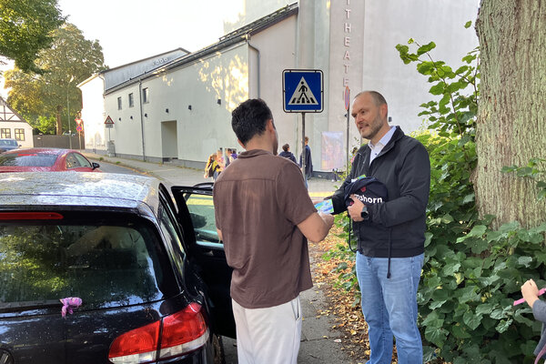 Bild vergr&ouml;&szlig;ern: Erster Stadtrat Michael Leeske im Gespr&auml;ch mit einer Person neben einem Pkw vor der Hafenschule in Elmshorn.
