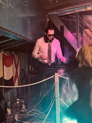 Bild vergr&ouml;&szlig;ern: Ein Mann mit Sonnenbrille, Hemd und Schlips am DJ-Pult.