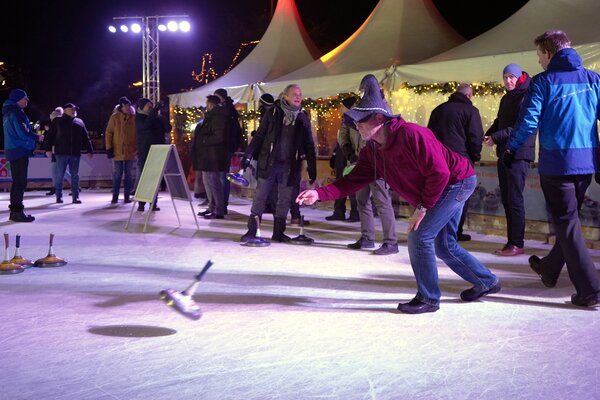 Bild vergr&ouml;&szlig;ern: Mehrere Personen auf einer Eisfl&auml;che beim Eisstockschie&szlig;en.