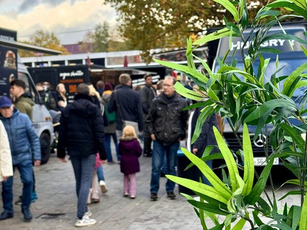 Viele Menschen gehen im Gang zwischen den Food Trucks.