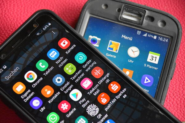 Zwei Smartphone liegen übereinander. Sie zeigen viele Symbole für Anwendungen.