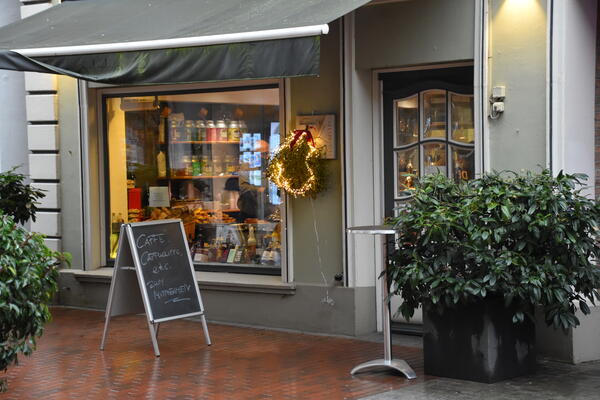 Weihnachtliche Dekoration an einem Café. Das Schaufenster spiegelt sich im Regen.