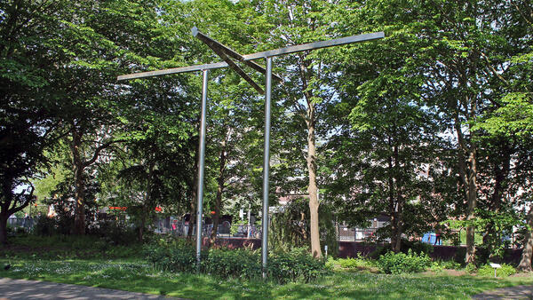Das Kunstwerk mit der Bezeichnung Brueckentor des Künstlers Bernd Wilhelm Blank ist aus dem Jahr 2003. Es befindet sich im Skulpturengarten. Das hohe Tor aus Stahl ist umringt von Bäumen während der Frühlingsblüte.