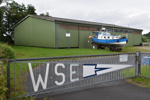 Bild vergr&ouml;&szlig;ern: Lagerhalle des Wasser-Sportvereins, vor der ein kleiner Kutter aufgebahrt ist.