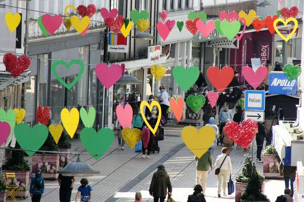 Girlanden mit großen bunten Herzen hängen zur Zierde über der Fußgängerzone Königstraße.