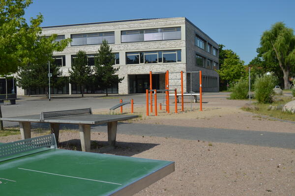 Neben einem großen Asphaltplatz sind ein paar Sandplätze mit Stangen und Tischtennisplatten.