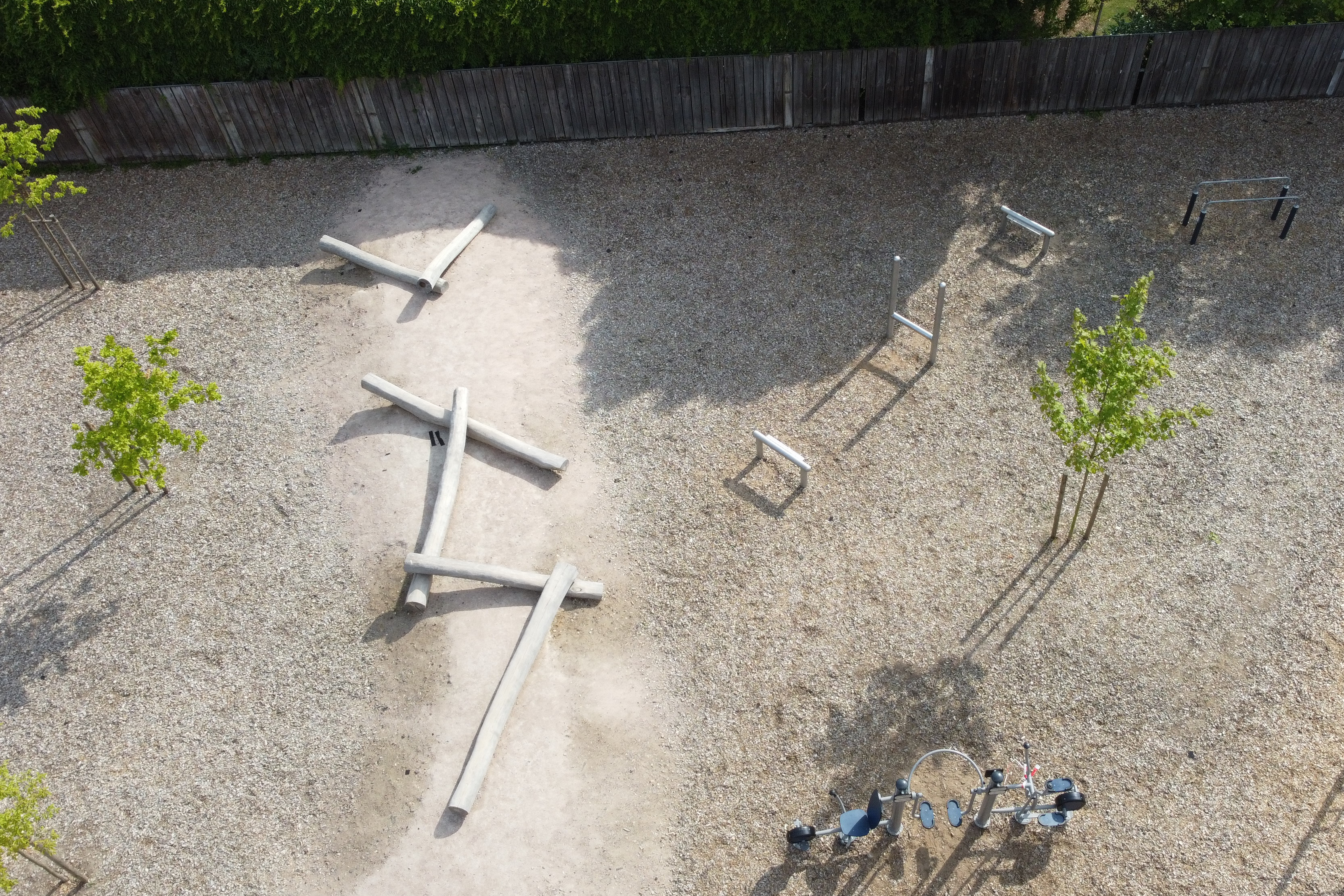 Ein Sandplatz mit verschiedenen Spielgeräten aus befestigten Metall- und Holzstangen.