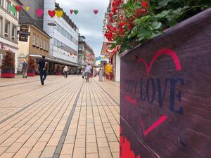 Blick entlang eines mit "City Love" beschrifteten Blumenkübels in der zentralen Königstraße.