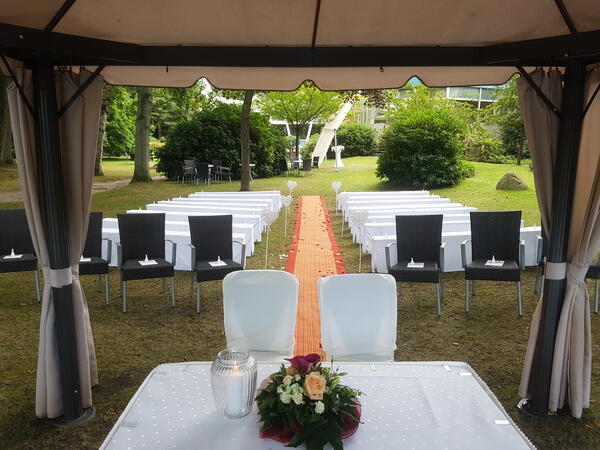 Der Tisch für das Brautpaar und die Stühle für die Gäste sind auf dem Rasen platziert.