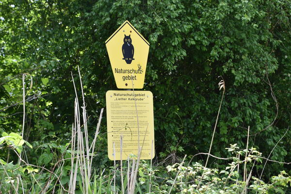 Ein gelbes  Naturschutzgebiet Hinweisschild mit einer Eule in der Liether Kalkgrube.