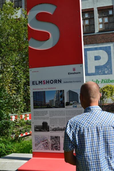 Ein Mann betrachtet die Informationstafel zum Stadtumbau Elmshorn.